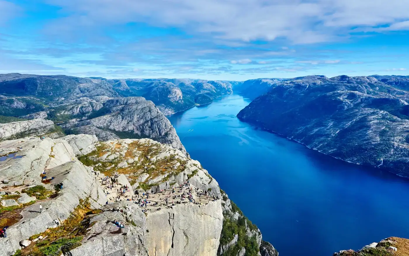 A fjord far below, seen from a clifftop where people are standing on the rock